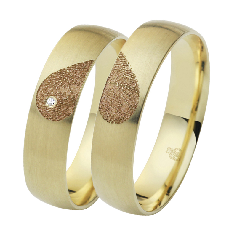 Aufnahme von Eheringen aus Gelbgold mit Diamanten und Herzmuster mit Fingerabdruck