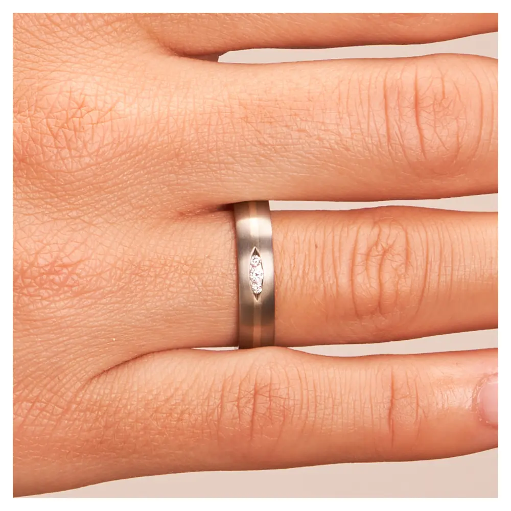 Titan Trauringe mit Diamanten in Vertiefung und Weißgoldstreifen auf Hand im Zoom