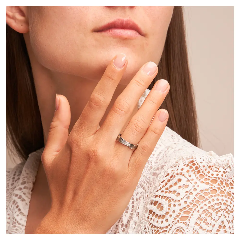 Eheringe aus Edelstahl und Titan mit 5 Diamanten auf Hand am Gesicht