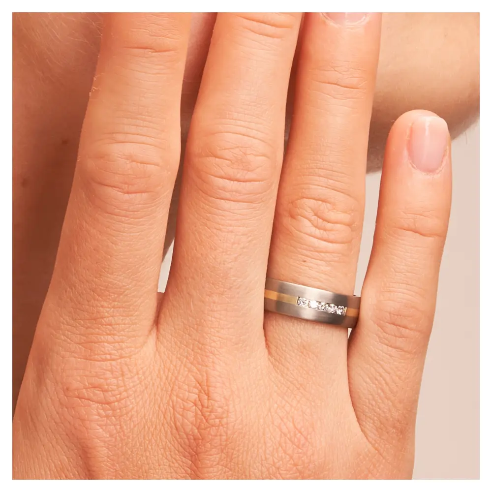 Titan Eheringe mit Gelbgoldstreifen und 5 Diamanten auf Hand am Gesicht in Zoom