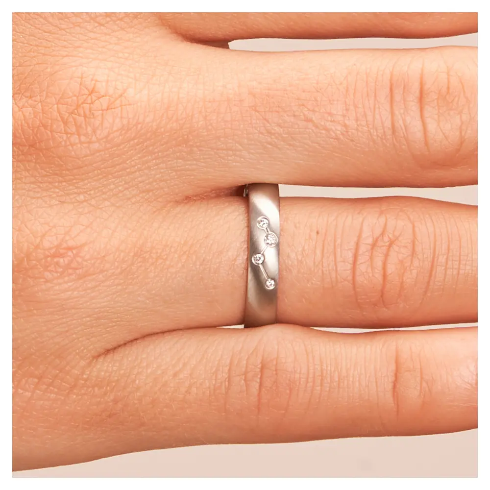 Quermatte Edelstahl Trauringe mit vier Diamanten in Sternbildmuster auf Hand im Zoom