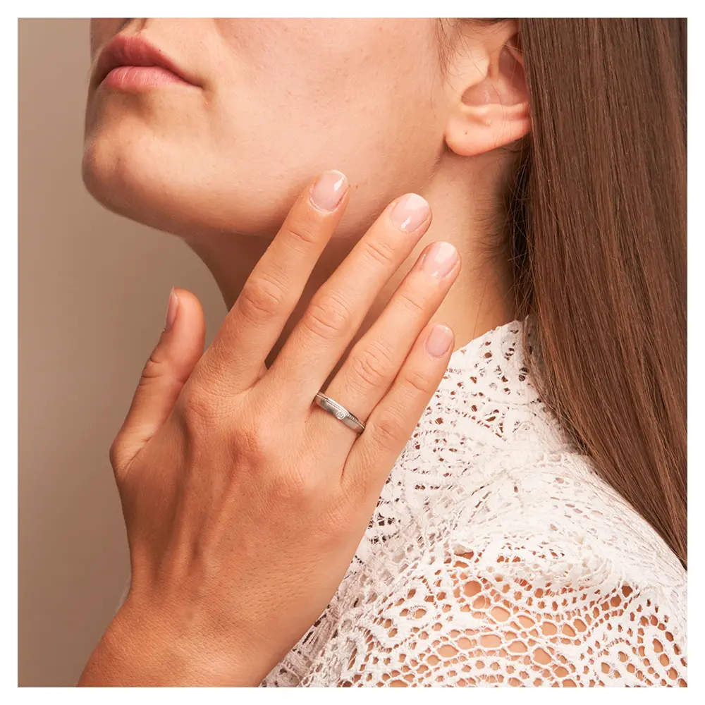 Eheringe aus Edelstahl mit Millgriff Muster und Diamanten auf Hand am Gesicht