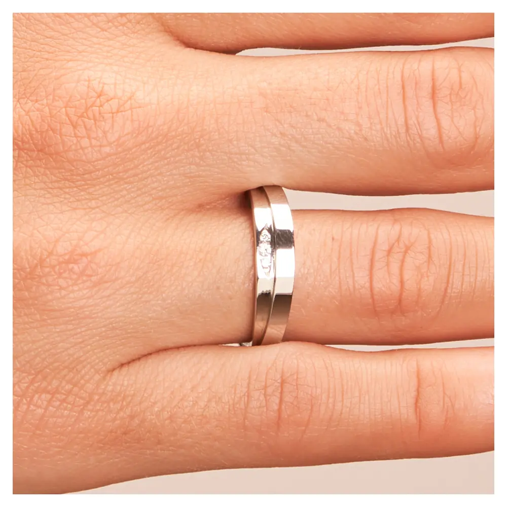 Polierte Edelstahl Trauringe mit gestuftem Design und drei Diamanten auf Hand im Zoom