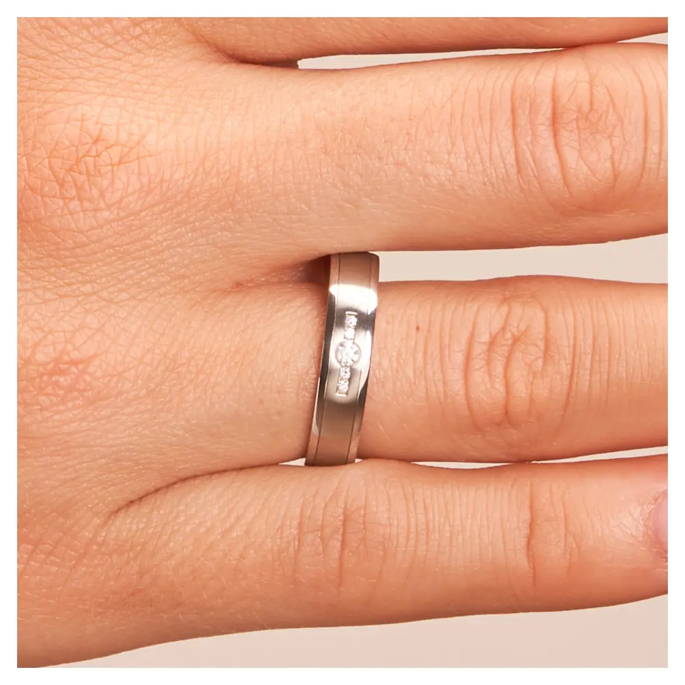 Edelstahl Trauringen längsmattiert mit vier kleinen und einem großen Diamanten auf Hand im Zoom