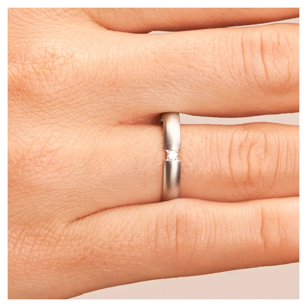 Trauringe aus quermattiertem Edelstahl mit Diamanten auf Hand im Zoom