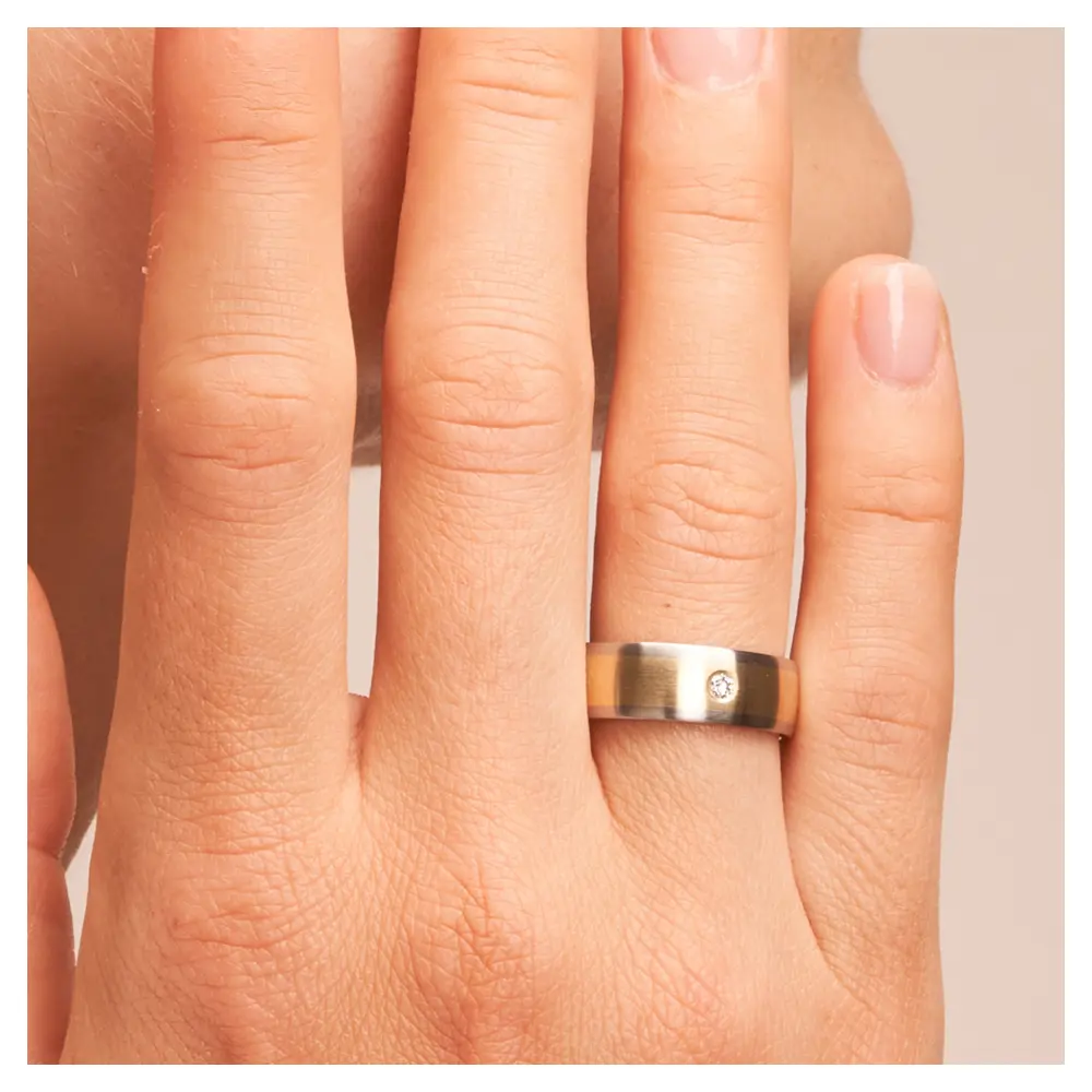 Stahl und Gelbgold Eheringe matt mit Diamanten auf Hand am Gesicht im Zoom