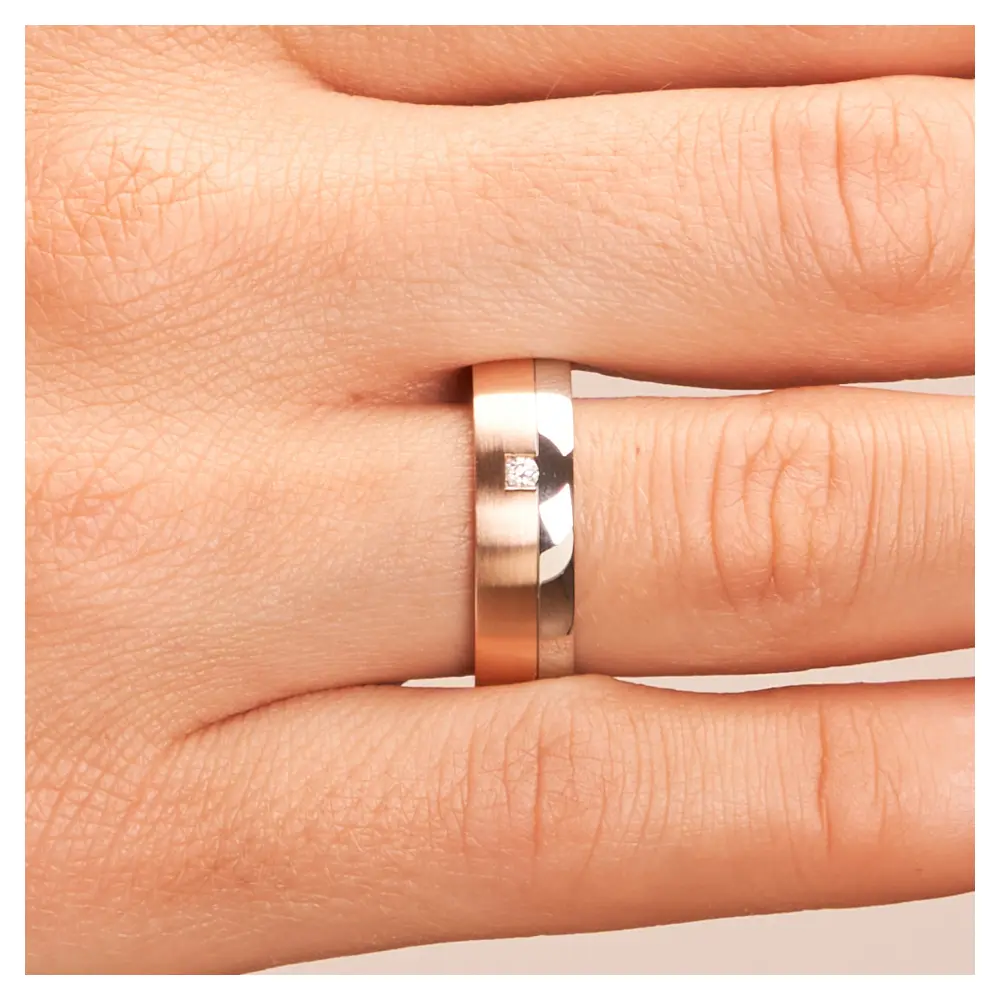 Mattierte Stahl&Rotgold Eheringe mit poliertem Streifen und Diamanten auf Hand im Zoom