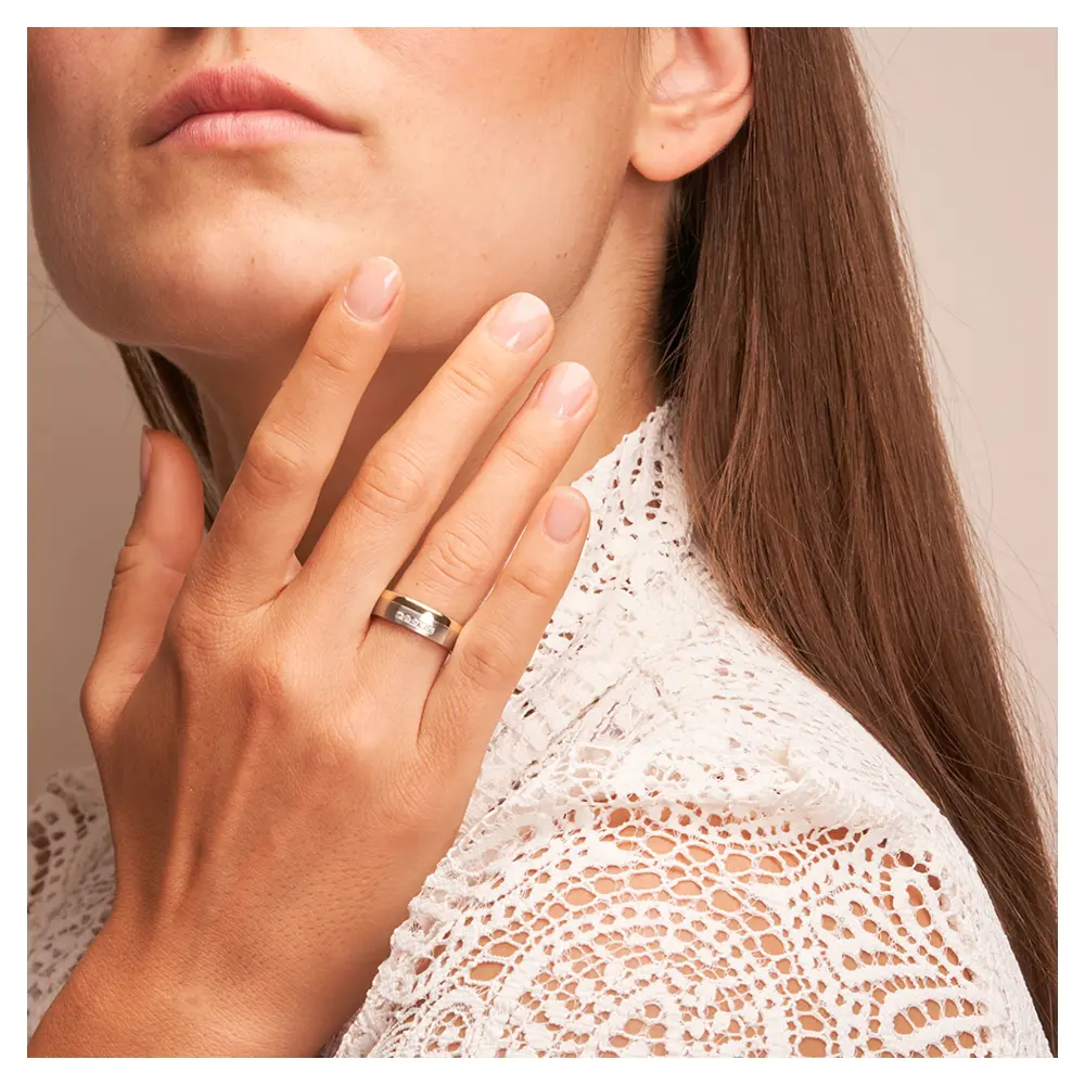 Stahl & Gelbgold Ehering mit Diamanten auf Hand im Gesicht