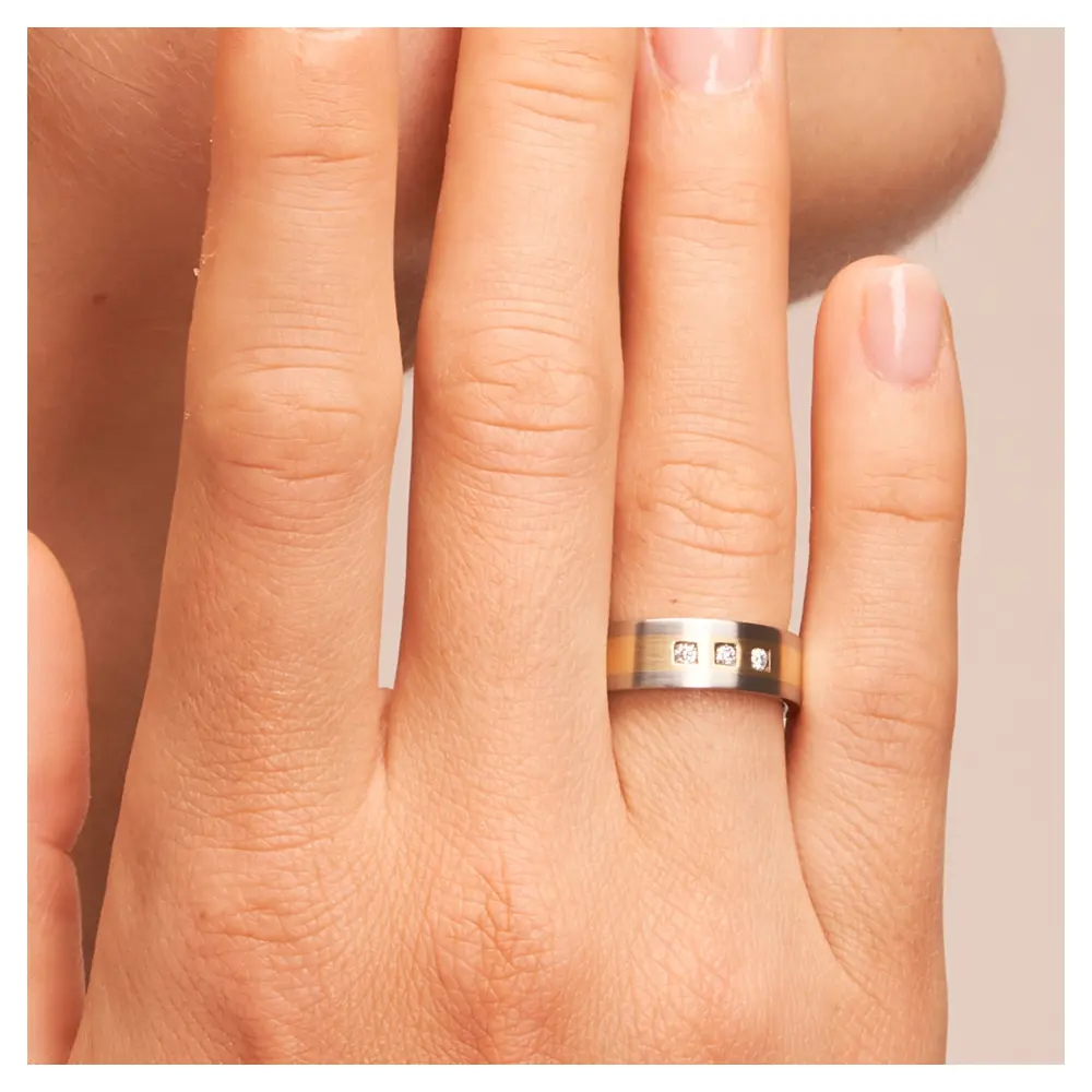 Stahl&Gelbgold Ehering Trauring mit Diamanten auf Hand am Gesicht im Zoom