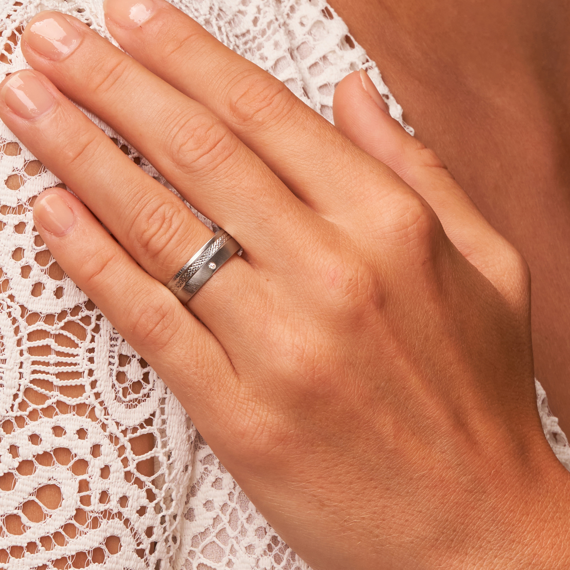 Quermattierter Palladium 500 Ehering mit gemustertem Streifen und Diamanten auf Hand in Nahaufnahme