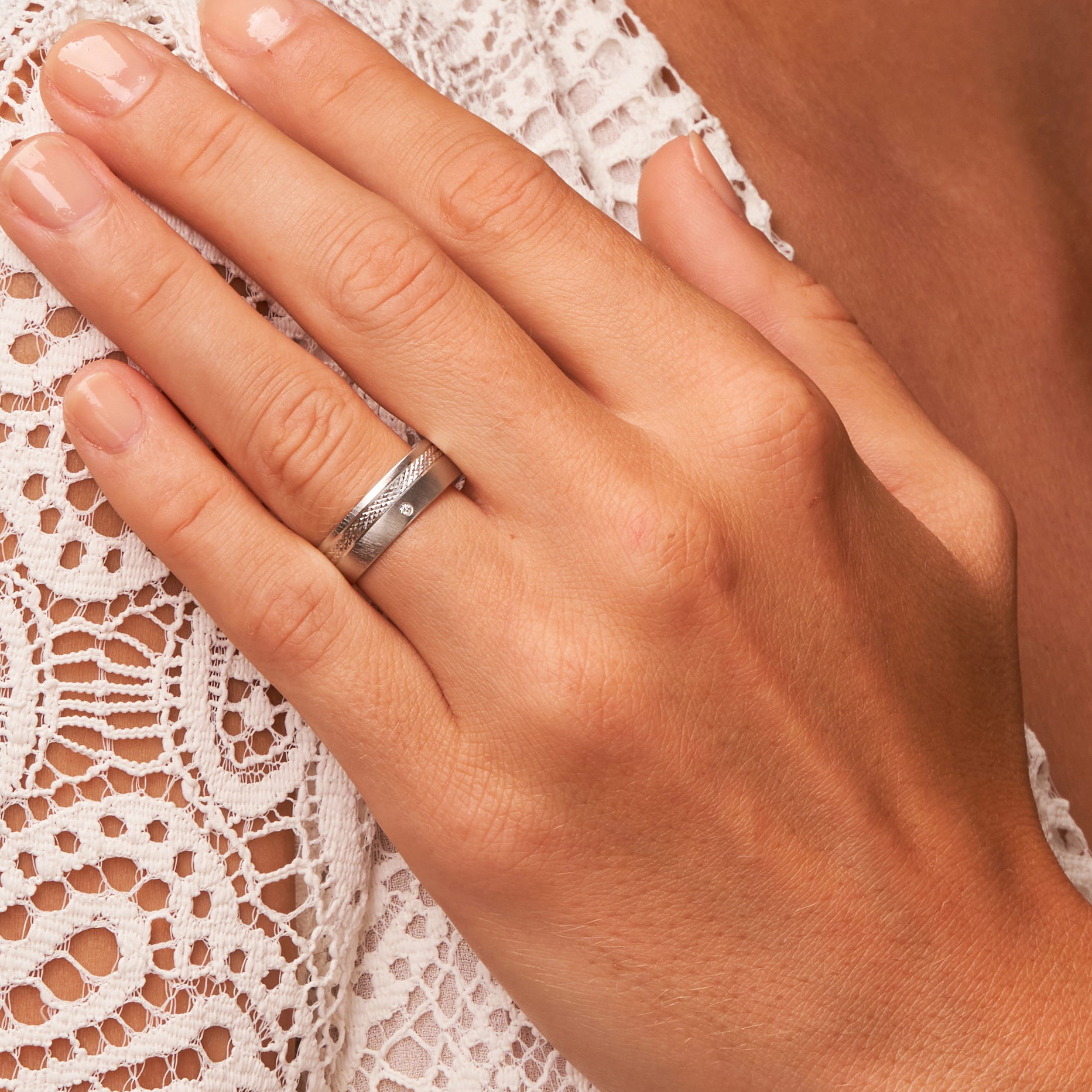 Quermattierter Platin Ehering mit gemustertem Streifen und Diamanten auf Hand in Nahaufnahme