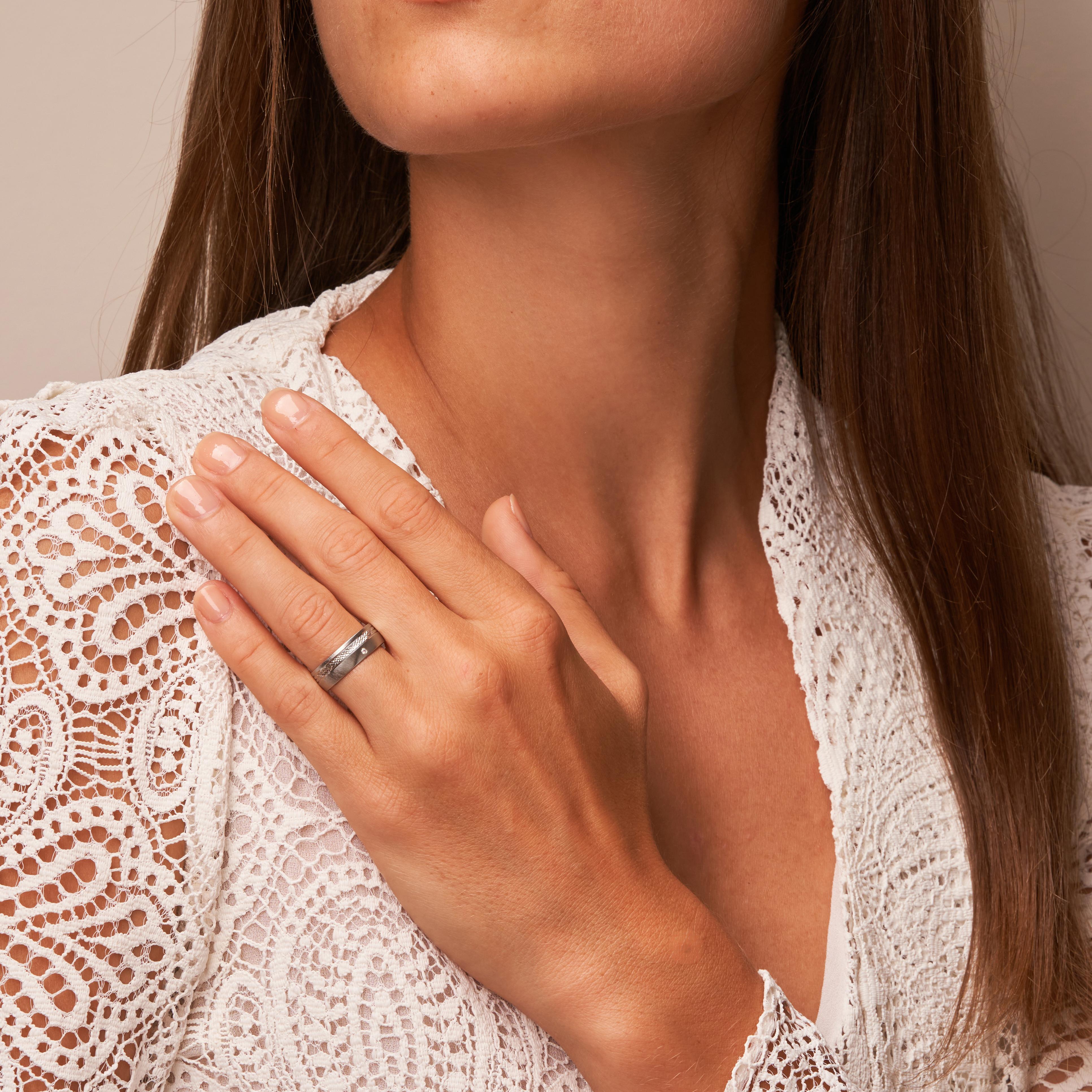 Quermattierter Palladium 500 Ehering mit gemustertem Streifen und Diamanten auf Hand am Gesicht
