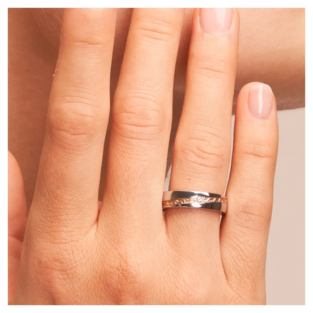 Trauring aus Edelstahl mit Roségoldstreifen und Diamanten auf Hand am Gesicht im Zoom
