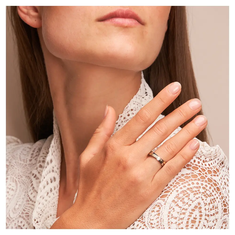 Edelstahl Ehering mit schrägem Gelbgoldstreifen und fünf Diamanten auf Hand am Gesicht