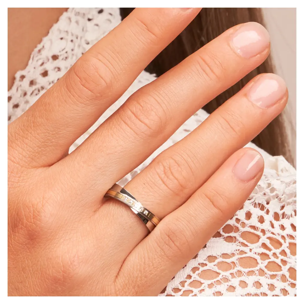 Edelstahl Ehering mit schrägem Gelbgoldstreifen und fünf Diamanten auf Hand am Gesicht im Zoom