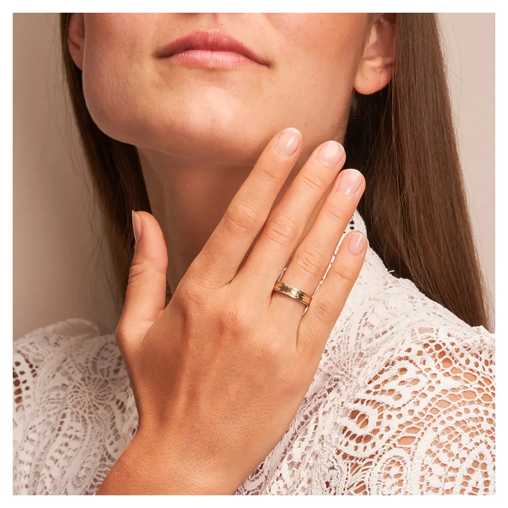 Gelbgold & Edelstahl Ehering mit strukturierter Oberfläche & Diamanten auf Hand am Gesicht