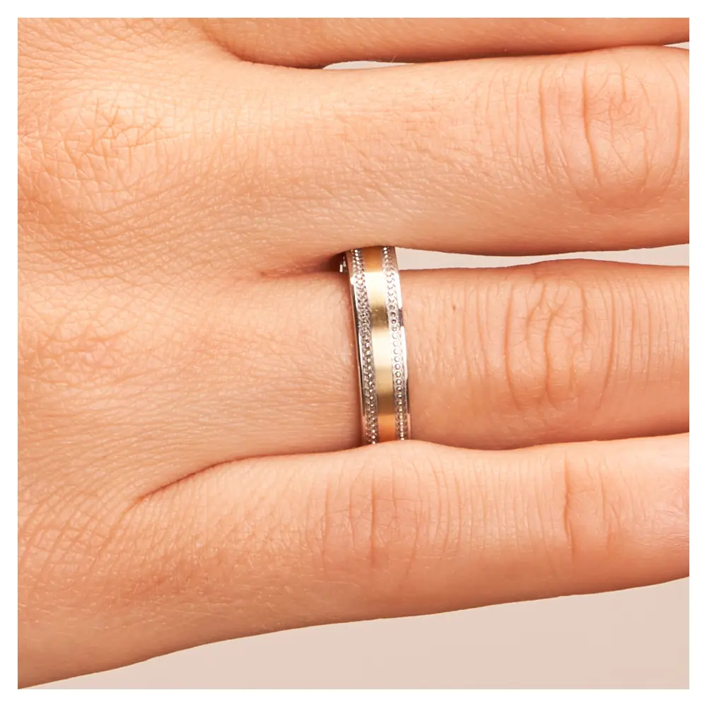 Ehering aus Edelstahl & Gelbgold in romatischem Design auf Hand im Zoom