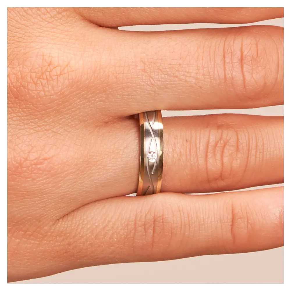 Trauringe aus Edelstahl & Gelbgold mit verspieltem Rillenmuster & Stein auf Hand im Zoom