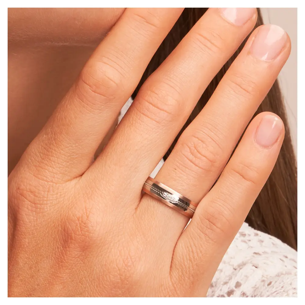 Ehering aus Edelstahl mit Roségoldrändern und drei Diamanten auf Hand am Gesicht im Zoom