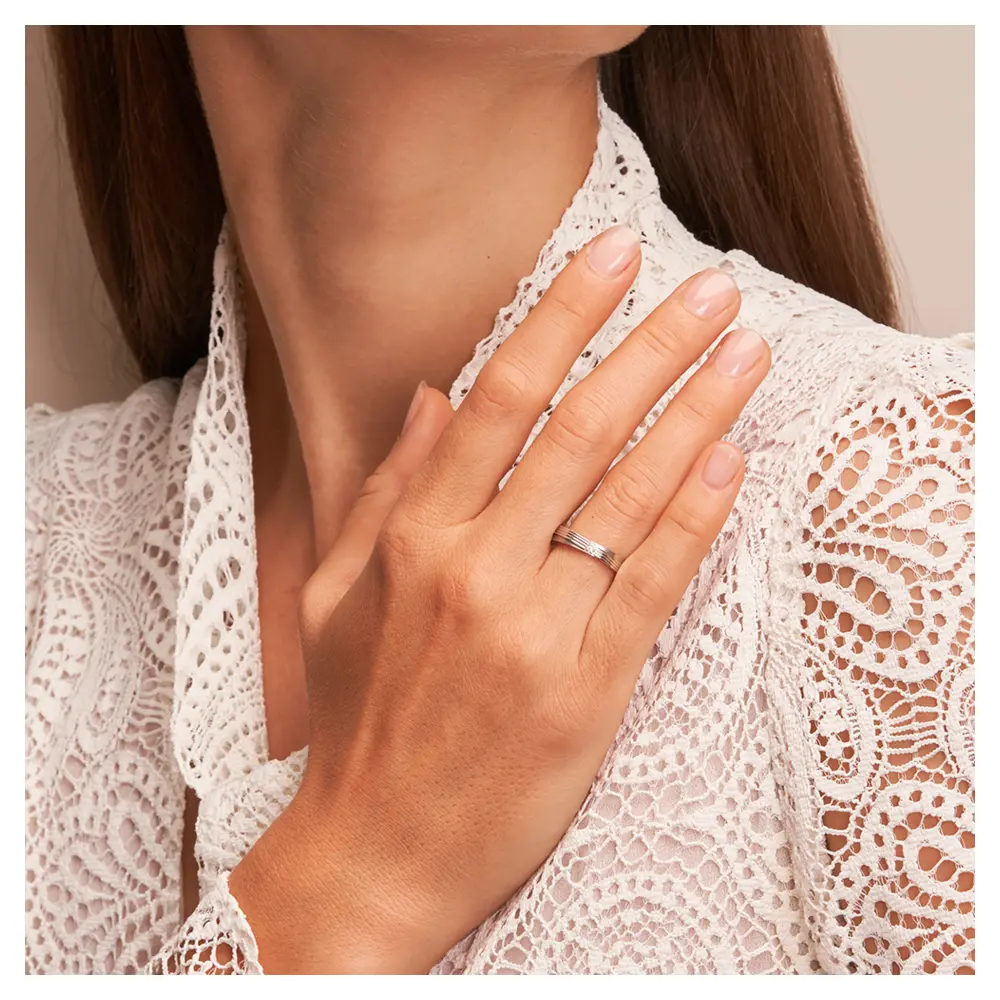In Stufen gestaltete Eheringe aus 925er Silber mit Diamanten und Rillen auf Hand am Gesicht