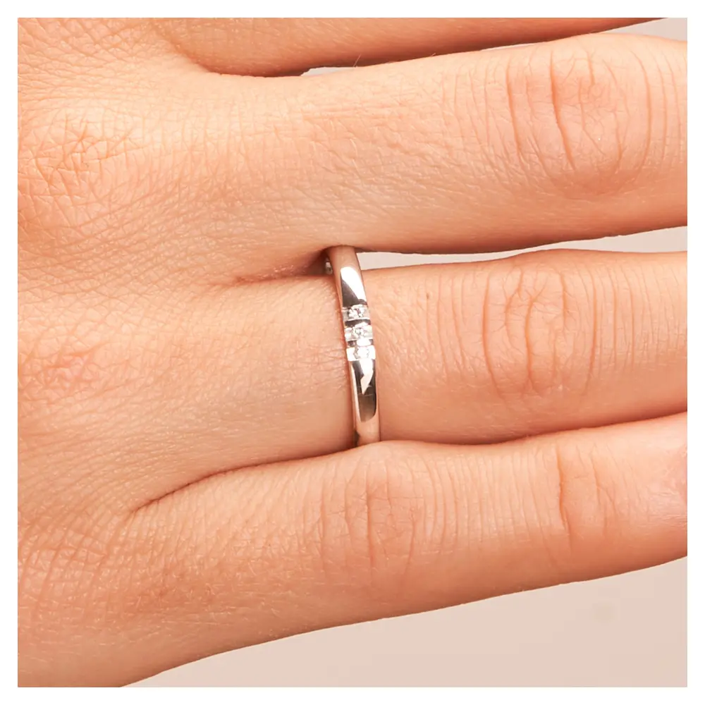 Schmale polierte Eheringe aus 925er Silber mit drei Diamanten auf Hand im Zoom