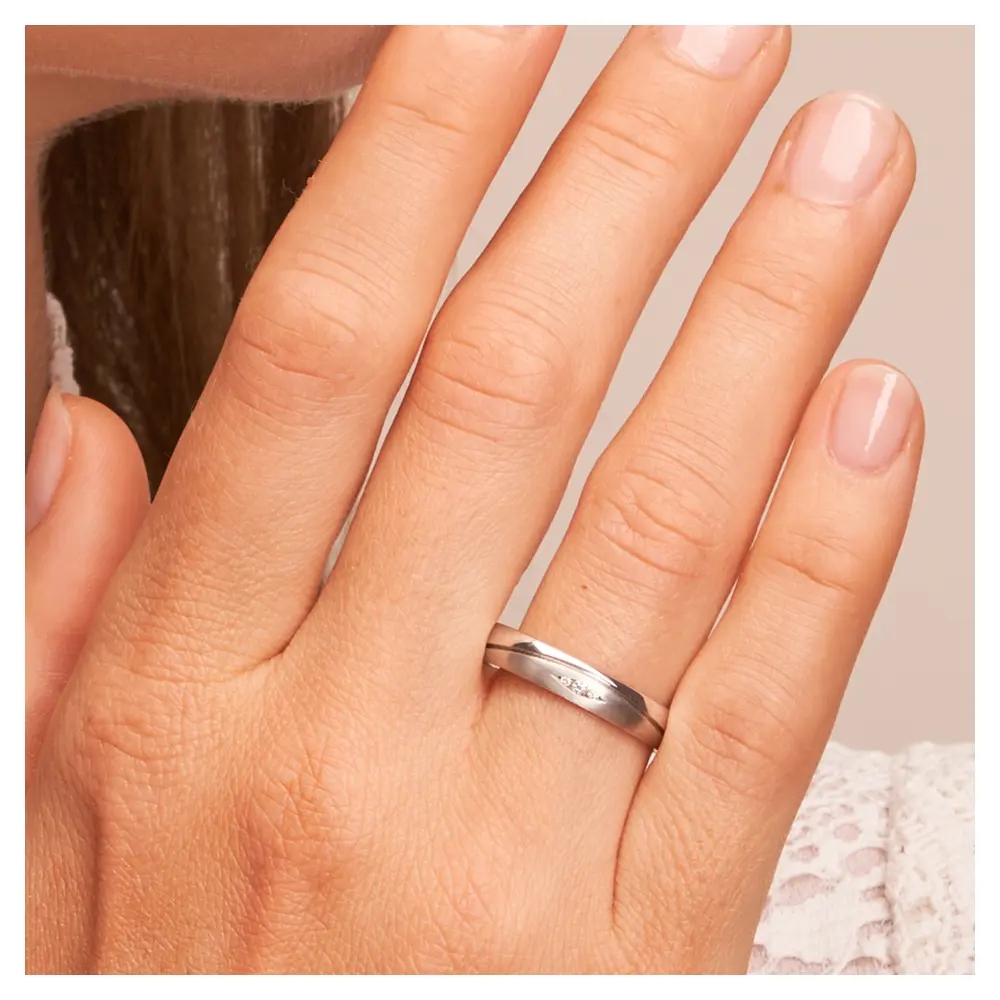 Ehering aus mattem und poliertem 925er Silber mit drei Diamanten auf Hand am Gesicht im Zoom