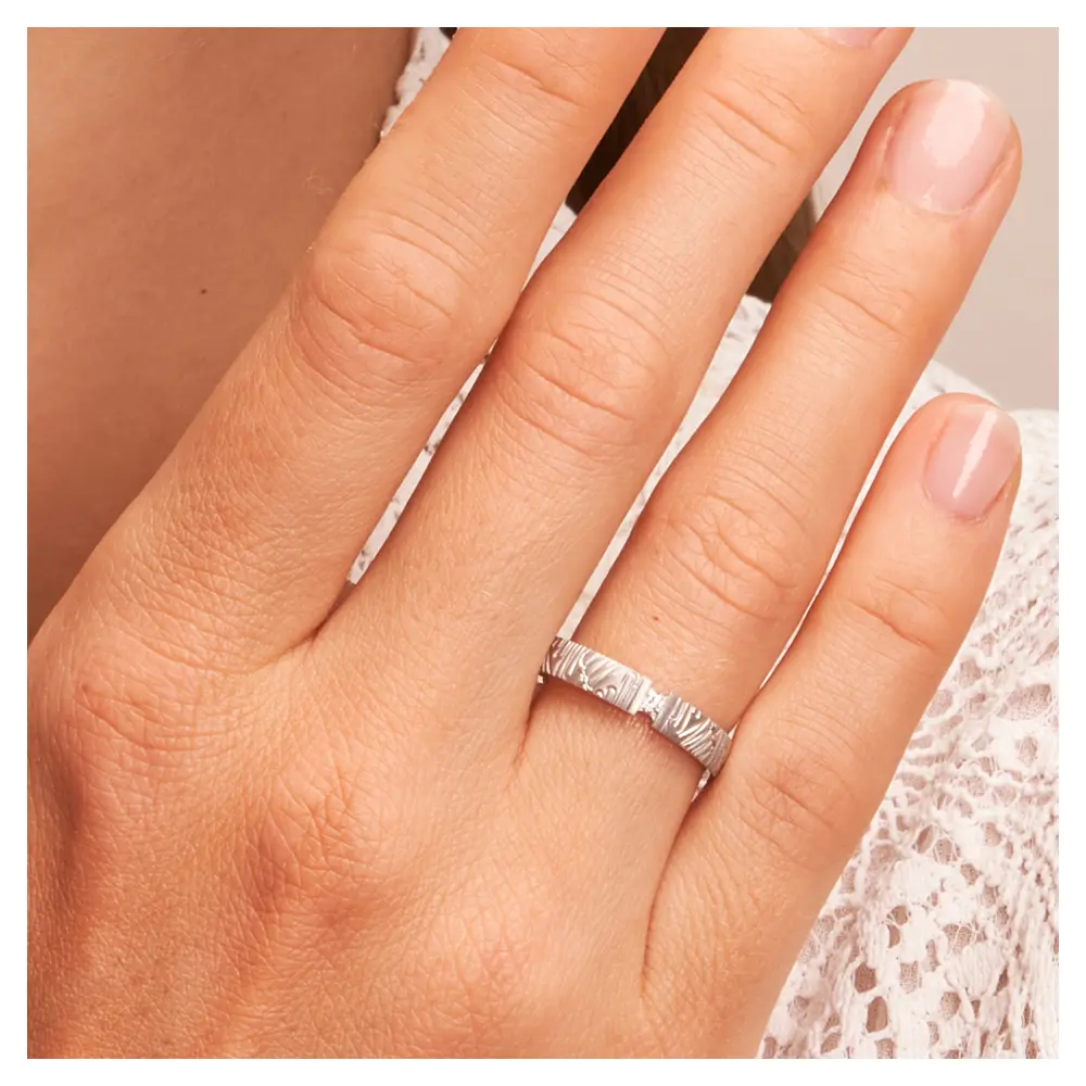 Ehering aus 925er Silber mit mattem Strukturdesign und Diamanten auf Hand am Gesicht im Zoom