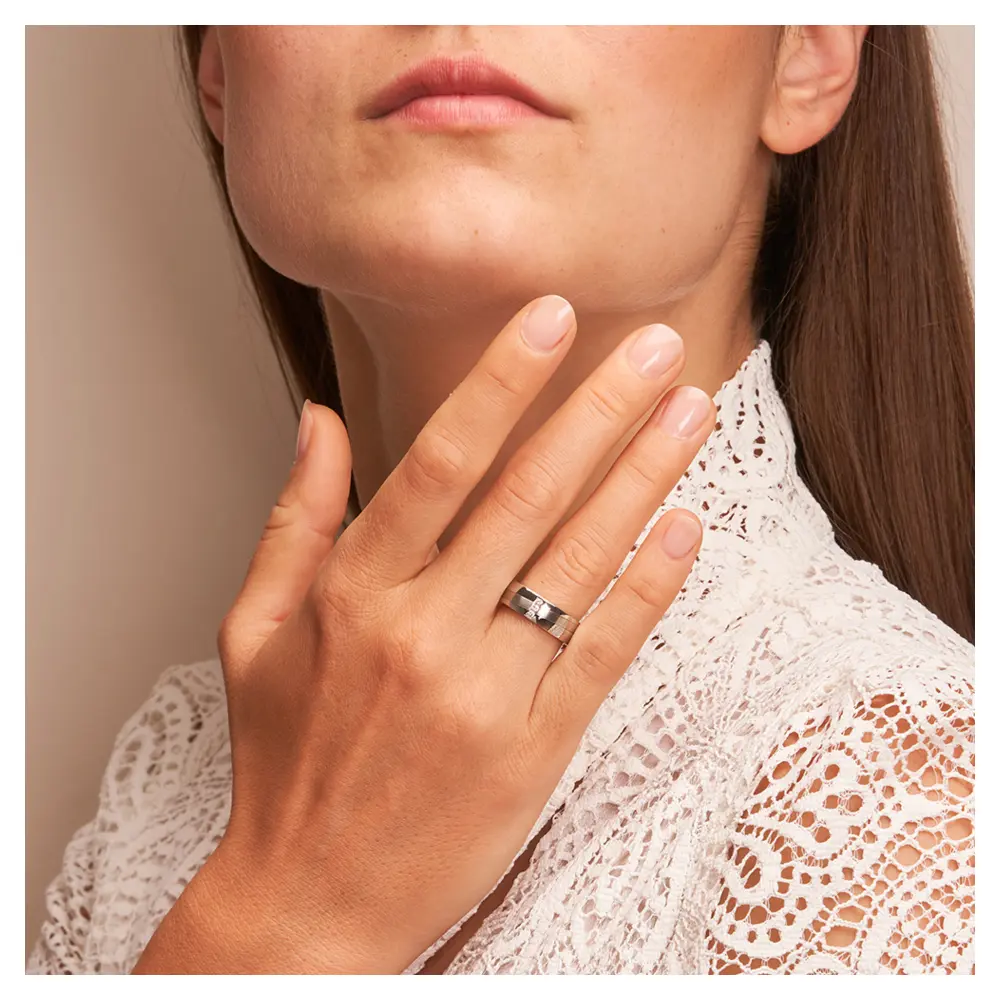 Stahl Eheringe mit 3 Diamanten und schrägem Streifen auf Hand am Gesicht
