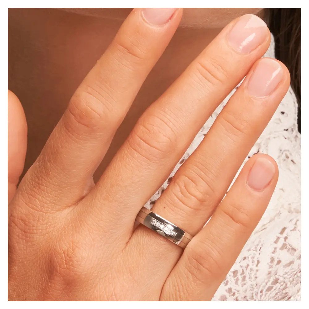 Edelstahl Eheringe mit 6 Diamanten auf mattem Mittelstreifen auf Hand am Gesicht im Zoom