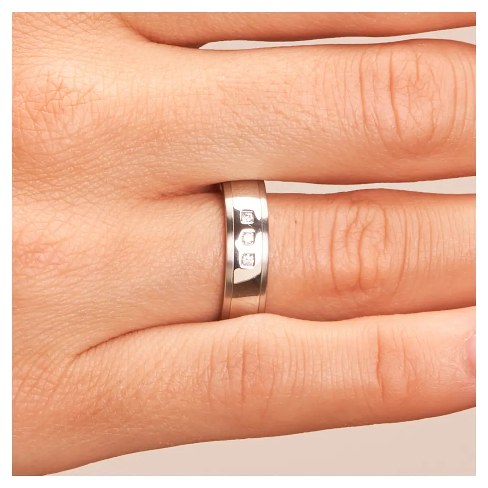 Hochpolierte Stahl Eheringe mit mattierten Rändern und 3 Diamanten auf Hand im Zoom