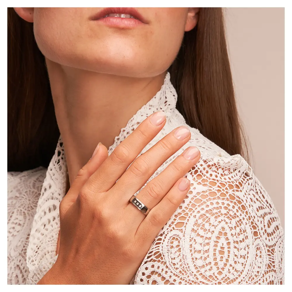 Hochpolierte Stahl Eheringe mit mattierten Rändern und 3 Diamanten auf Hand am Gesicht