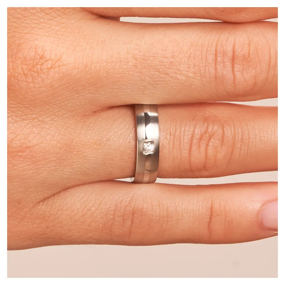 mattierte Stahl Eheringe mit poliertem Streifen und Diamanten auf Hand im Zoom