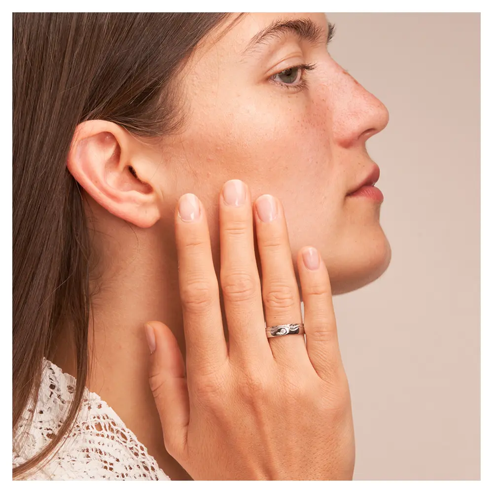 Silber 925 Trauring mit wellig designter Oberfläche und Diamanten auf Hand am Gesicht
