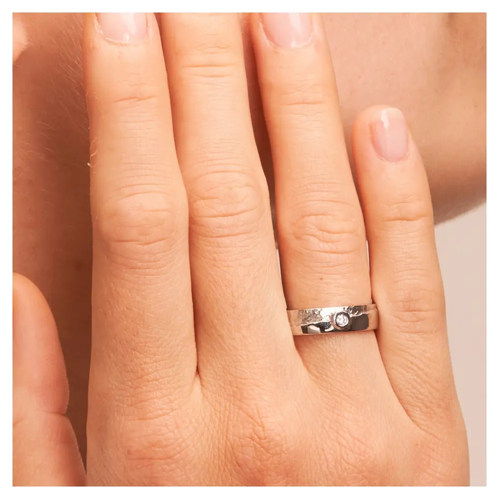 Silber 925 Trauring mit matter Strukturierung und Diamanten auf Hand am Gesicht im Zoom