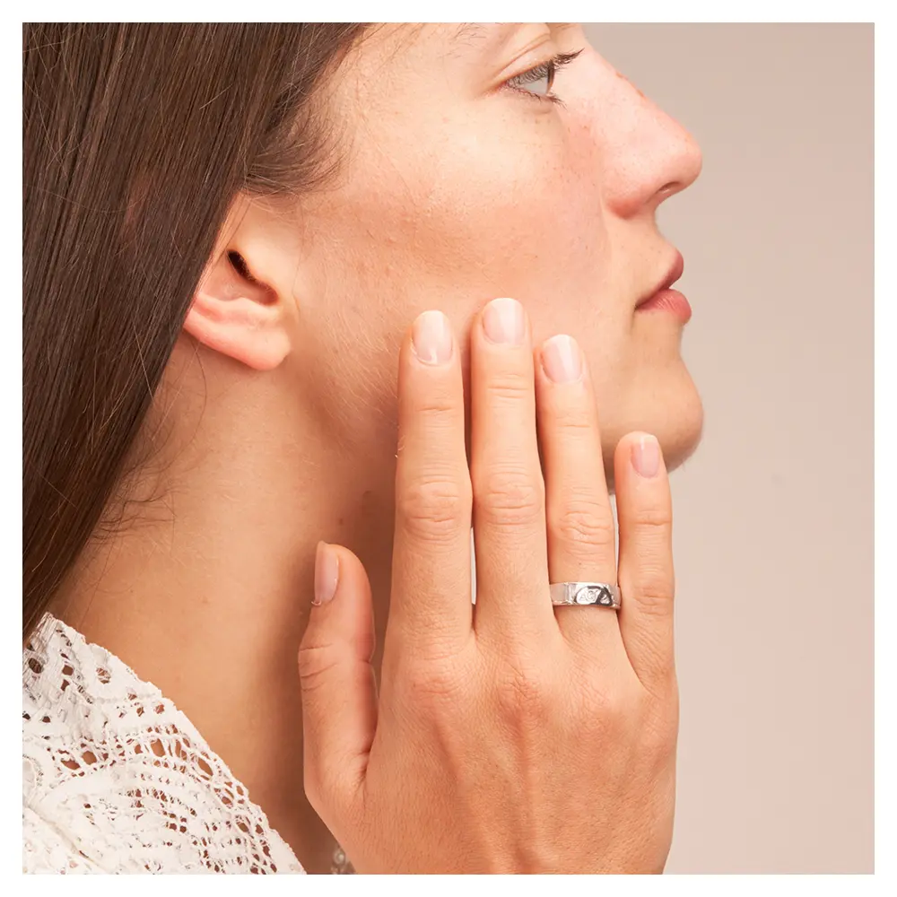 Strukturierte Silber 925 Eheringe mit Peace Zeichen und Diamanten auf Hand am Gesicht