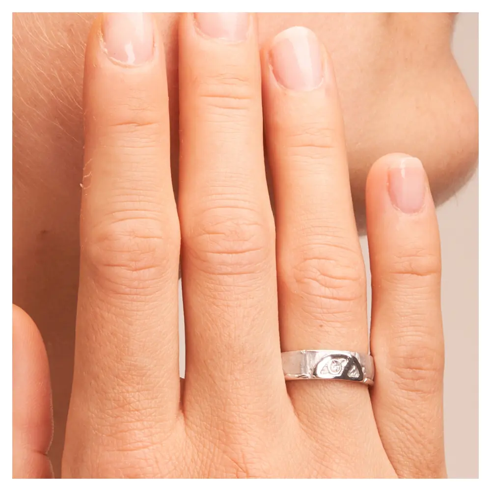 Strukturierte Silber 925 Eheringe mit Peace Zeichen und Diamanten auf Hand am Gesicht im Zoom