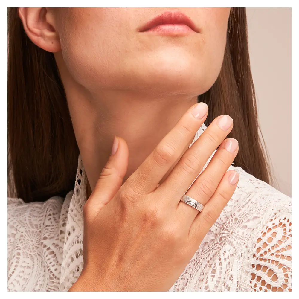 Strukturierte Silber 925 Eheringe mit ringübergreifender Spirale und Diamanten auf Hand am Gesicht