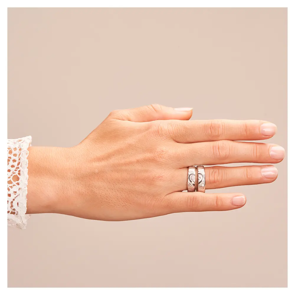 Silber 925 Eheringe mit ringübergreifendem Herz und Diamanten auf Hand