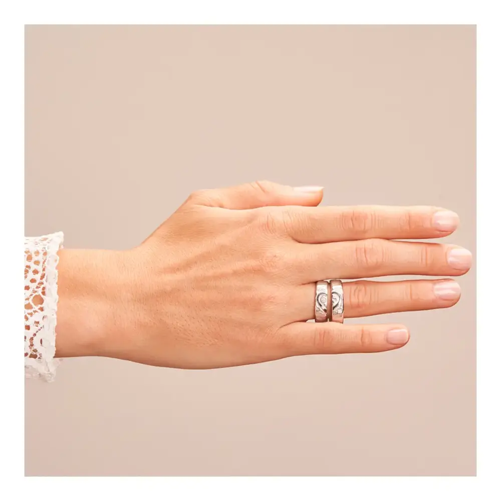 Weißgold Eheringe mit ringübergreifendem Herz und Diamanten auf Hand