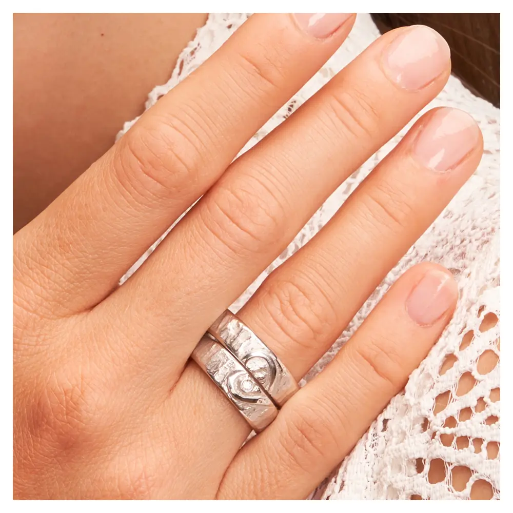 Silber 925 Eheringe mit ringübergreifendem Herz und Diamanten auf Hand am Gesicht