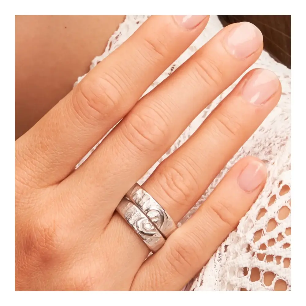 Weißgold Eheringe mit ringübergreifendem Herz und Diamanten auf Hand im Zoom