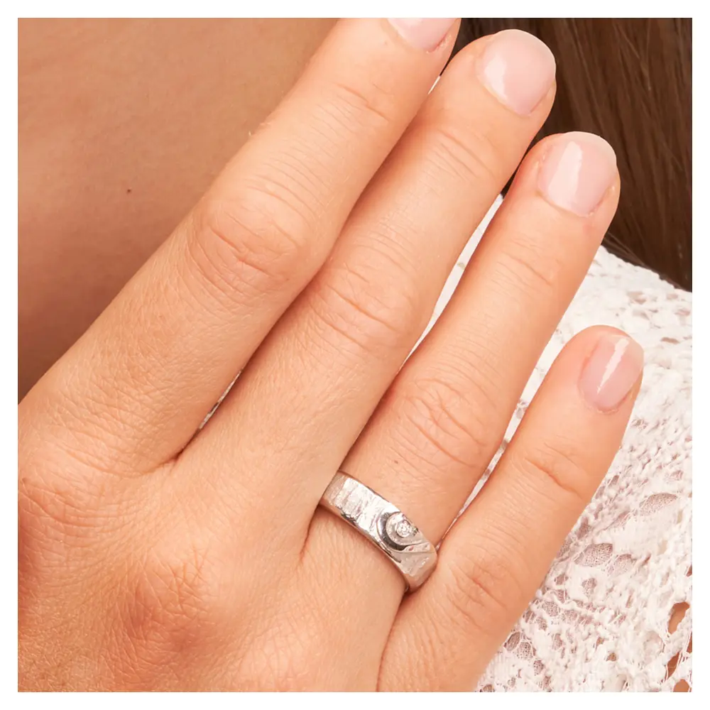 Silber 925 Eheringe mit ringübergreifendem Herz und Diamanten auf Hand am Gesicht im Zoom