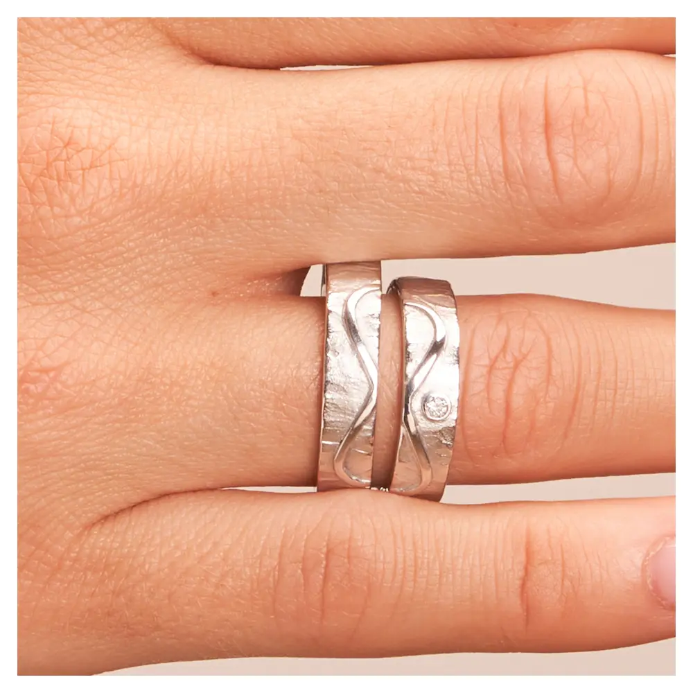Strukturierte Silber 925 Eheringe mit Unendlichkeit Muster und Diamanten auf Hand im Zoom