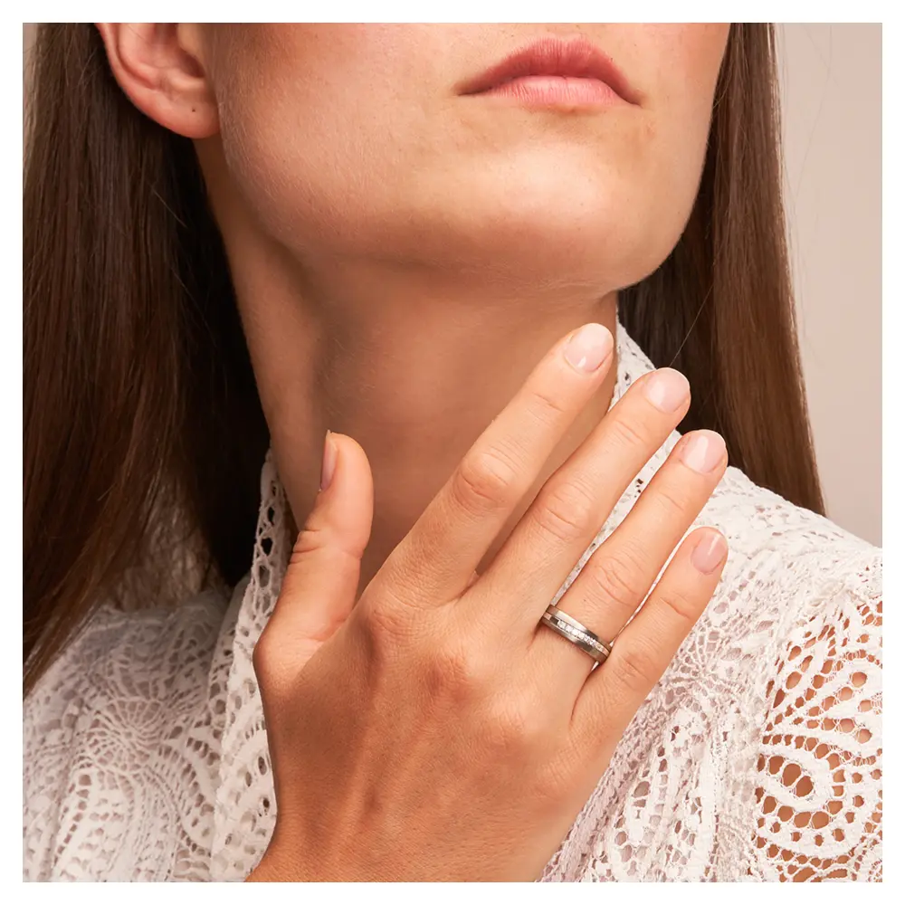Eheringe aus Titan mit poliertem Weißgoldstreifen und 6 Diamanten auf Hand am Gesicht