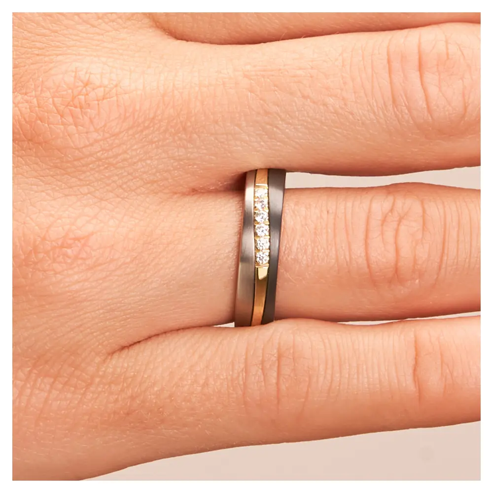 Ehering aus Titan mit Streifen aus Gelbgold und Zirkonium und Diamanten auf Hand im Zoom
