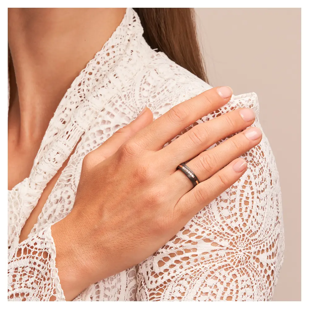Ehering aus schwarzem Zirkonium mit poliertem Roségoldstreifen und 6 Diamanten auf Hand am Gesicht