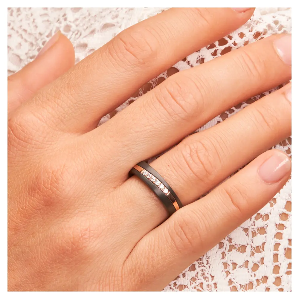 Ehering aus schwarzem Zirkonium mit Roségoldstreifen und 6 Diamanten auf Hand am Gesicht im Zoom