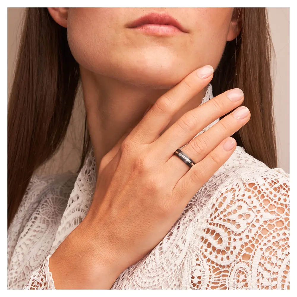 Ehering aus Weißgold & Zirkonium mit 6 Diamanten in bicolorem Design auf Hand am Gesicht