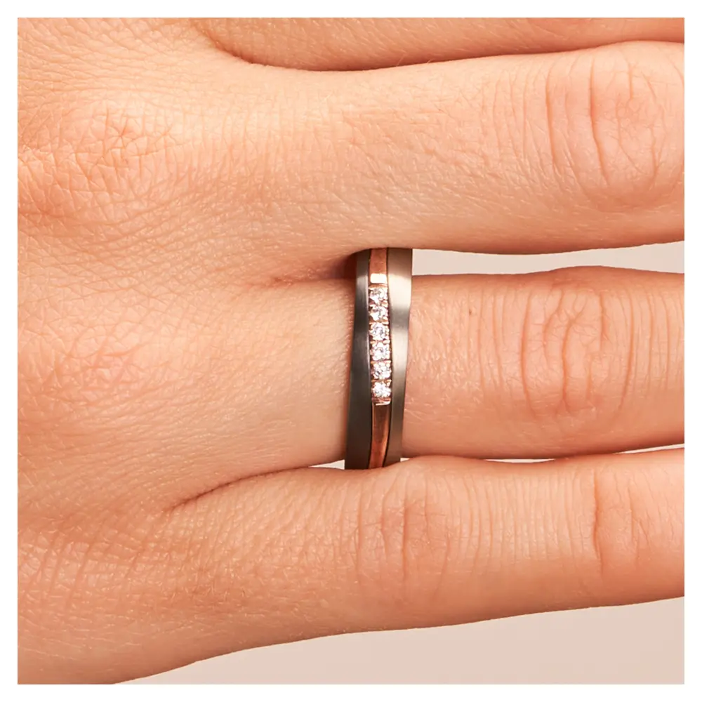 Ehering aus Titan mit Streifen aus Roségold und Zirkonium und Diamanten an Hand im Zoom
