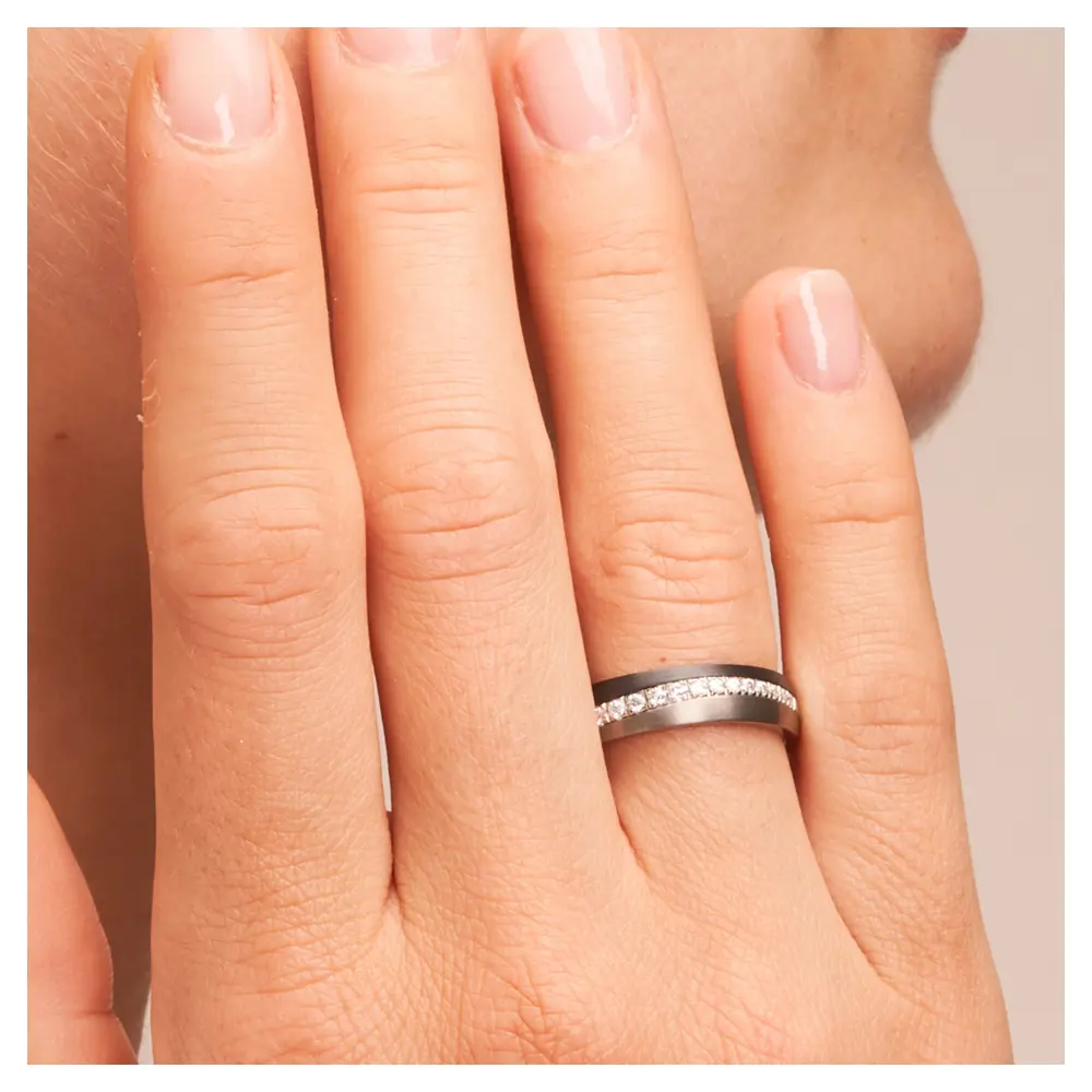 Ehering aus Titan&Weißgold&Zirkonium mit Diamanten auf Hand am Gesicht im Zoom